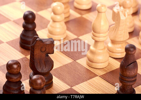 Nahaufnahme der Schach Spiel mit den weißen und schwarzen log Stücke auf braun Schachbrett. Kampf oder Rivalen mit Pferd und Bauern. Stockfoto