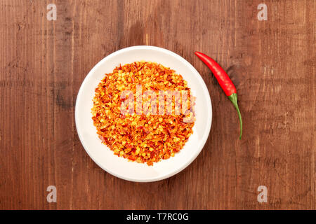 Red Hot Cayenne Pfeffer, gemahlen und frische Chili, Schuß von der Oberseite in einem dunklen Holzmöbeln im Landhausstil Hintergrund mit einem Platz für Text Stockfoto