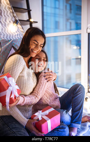 Foto eines glücklichen jungen Frau mit ihrer kleinen Tochter Mädchen Spaß am Boden Betrieb vorhanden Geschenkboxen. Weihnachten Konzept. Stockfoto