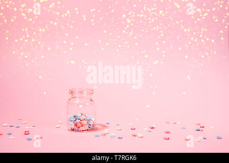 Kleine Flasche mit kleinen Sternen Konfetti auf rosa Hintergrund. Urlaub Konzept. Stockfoto