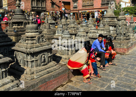 Lokalen Familie in bunten Kleidern auf einem Platz mit Stupas auf der Website der Swayambhunath Tempel oder Monkey Tempel ruht, Kathmandu, Nepal Stockfoto