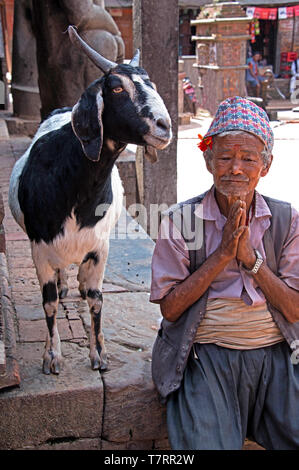 Ältere Menschen mit seiner Ziege gruss Besucher zu einem Innenhof in einem nepalesischen Dorf Kathmandu, Nepal Stockfoto