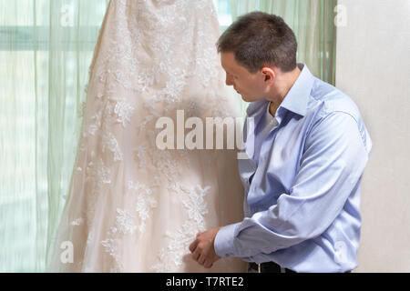 Mann Bräutigam bei der Hochzeit Kleid auf der Suche nach Fenster Fensterbänke in städtischen moderne Stadt Hotel Apartment vor der Zeremonie Stockfoto