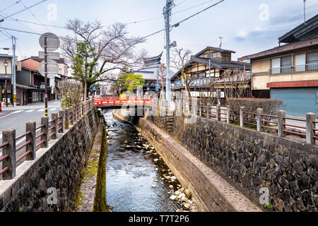 Takayama, Japan - April 7, 2019: Kleine rote Brücke von Enako Fluss in der Präfektur Gifu in Japan mit Wasser im frühen Frühling im traditionellen Dorf Stockfoto