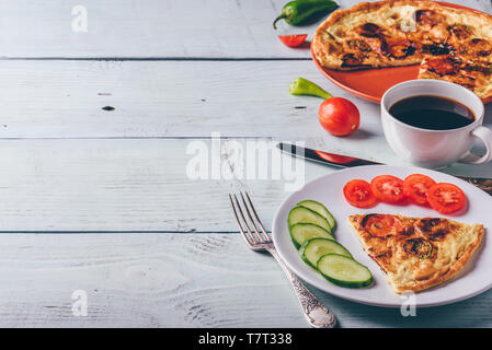 Frühstück frittata mit Chorizo, Tomaten und Chilischoten auf Teller und Tasse Kaffee über hellen Hintergrund. Gesundes Essen, das Konzept. Stockfoto
