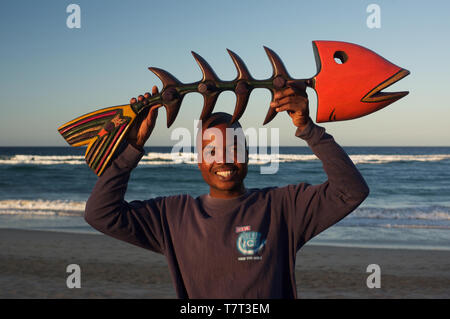 Lokale Mann mit einem geschnitzten Fisch in Ponta de Ouro Beach, Mosambik Stockfoto