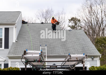 Haus während des Tages über Garage mit Lkw, Grau Farbe Einfamilienhaus und Mann zu Fuß auf Dachschindeln und Leiter während der Reparatur Stockfoto