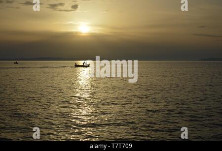 Angeln Boot im Sonnenuntergang, die in der Sun Beam gefangen Stockfoto