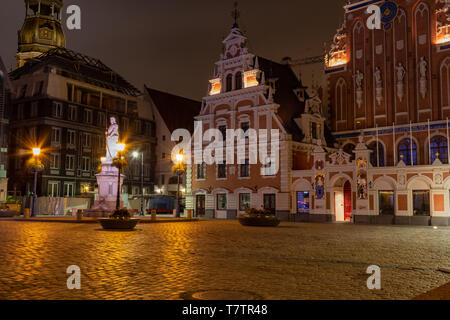 Die Altstadt von Riga die lettische Hauptstadt bei Nacht. Schwarzhäupterhaus in der Rathausplatz und der Turm der Kathedrale im historischen Zentrum des alten Stockfoto