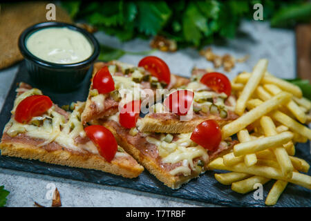 Club Sandwich mit Käse, eingelegte Cucmber, Tomate und geräuchertem Fleisch. Mit Pommes Frites garniert Stockfoto