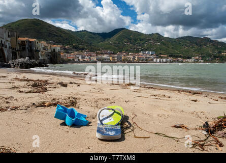 Flip Flop und angeschwemmte Seegras am Strand von Cefalù, Sizilien. Stockfoto