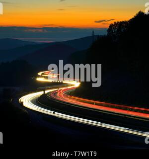 Autobahn A3 schlängelt sich durch Mittelgebirge Landschaft, leichte Spuren in der Dämmerung, Spessart, Bayern, Deutschland Stockfoto