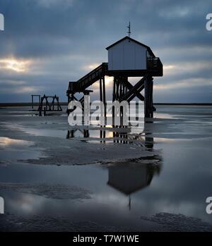 Haus am See bei Ebbe am Strand bei Sonnenaufgang, dunkle Wolken, St. Peter-Ording, Nationalpark Schleswig-Holsteinisches Wattenmeer, Schleswig-Holstein, Deutschland Stockfoto