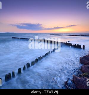 Sonnenuntergang am Strand der Ostsee, Überschreiten der x-förmigen Buhnen, am Horizont Hiddensee, Insel Rügen, Mecklenburg-Vorpommern, Deutschland Stockfoto