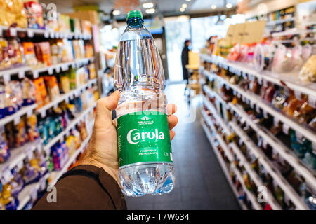 Paris, Frankreich, 27.Dezember, 2017: der Mensch hand POV persönliche Perspektive holding Carola Mineralwasser im modernen Supermarkt mit mehreren Produkt in den Regalen Stockfoto