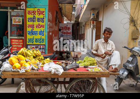 Straßenszene in Mahipalpur Bezirk, einem Vorort von Delhi Flughafen in New Delhi, die Hauptstadt Indiens: lokaler Mann Straße Händler besucht einen Karren mit Obst Stockfoto