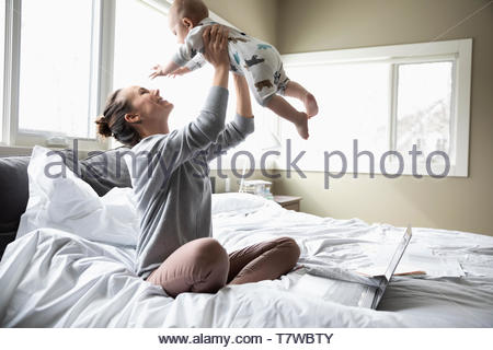 Glückliche Mutter spielt mit Baby Sohn am Bett