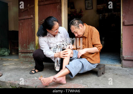 Die katholische Schwester Marie Binh (55) aussieht, nachdem der Agent Orange Opfer Minh lange Nguyen (64), lebt mit seinem Nächsten. Phu Ly Dorf (Ha Nam Provinz) in der Nähe von Hanoi, Vietnam Stockfoto