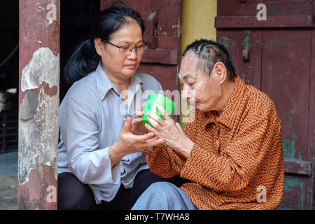 Die katholische Schwester Marie Binh (55) aussieht, nachdem der Agent Orange Opfer Minh lange Nguyen (64), lebt mit seinem Nächsten. Phu Ly Dorf (Ha Nam Provinz) in der Nähe von Hanoi, Vietnam Stockfoto