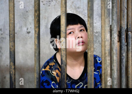 Agent Orange Opfer Mädchen (26) lebt in einem Käfig auf hölzernen Schieferboden. Während des Tages, die Mutter hat keine Zeit, sich um ihre kranke Tochter. Tu Chau Village in der Nähe von Hanoi, Vietnam, Asien Stockfoto