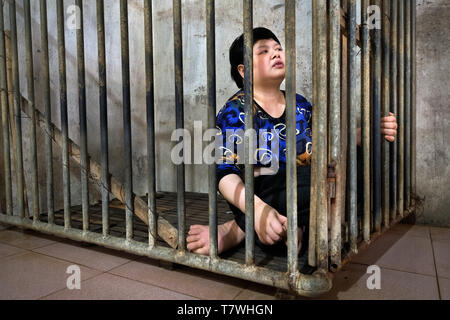 Agent Orange Opfer Mädchen (26) lebt in einem Käfig auf hölzernen Schieferboden. Während des Tages, die Mutter hat keine Zeit, sich um ihre kranke Tochter. Tu Chau Village in der Nähe von Hanoi, Vietnam, Asien Stockfoto