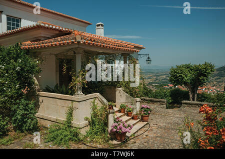 Altes haus Fassade mit Treppe zur Terrasse voller Blumen, auf hügeligen Landschaft bei Monsanto. Eine nette und besondere historische Dorf von Portugal. Stockfoto