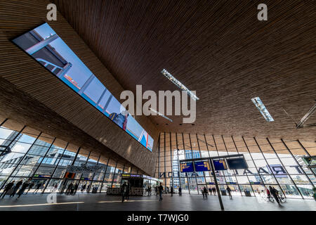 ROTTERDAM, 13. April 2019 - Rotterdam Bahnhof Struktur, die auf die modernen Gebäude und eine Straßenbahn warten auf Reisende unter einem sonnigen Tag leuchtet Stockfoto