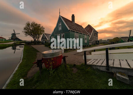 Lange Belichtung von sunrise Reflexion der Holz- grüne Häuser mit dunklen orange Farbe Dach spiegelt sich auf dem ruhigen Wasser des Kanals Stockfoto