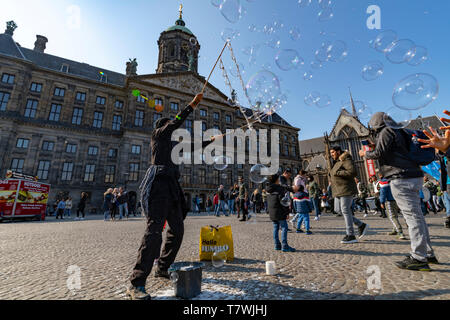 AMSTERDAM, 14. April 2019 - Wasser ballon Gebläse spielen mit Kinder und Kinder auf dem Dam Platz in Amsterdam unter einem sonnigen hellen Himmel Stockfoto