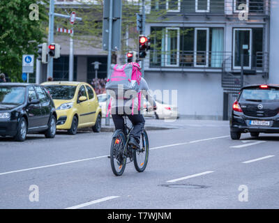 Augsburg, Deutschland - 5. Mai 2019: Delivery Man mit dem Fahrrad im Verkehr mit Lebensmitteln, in lila Farbe Stockfoto