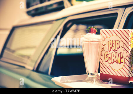 Fach auf eine 60er Auto mit Popcorn und eine Erdbeer Milchshake Stockfoto