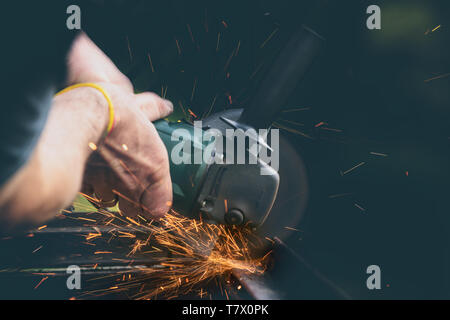 Mann mit Winkelschleifer, Schneiden von Metall, eine Menge blinken die Funken fliegen. Stockfoto