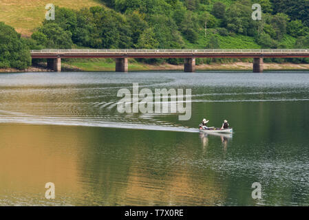 Angler auf Wimbleball Lake mit bessom Bridge im Hintergrund. Teil des Exmoor National Park in Somerset, England, Großbritannien Stockfoto