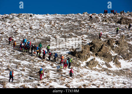 Eine Gruppe von Bergsteigern ist zu Fuß in die schneebedeckten Berge zu Spitze. Stockfoto