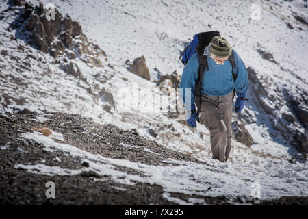 Eine alte Kletterer ist zu Fuß in die schneebedeckten Berge. Stockfoto