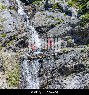 Zwei Radfahrer überquert einen kleinen Wasserfall an einer steilen Felswand auf Single Trail Stockfoto