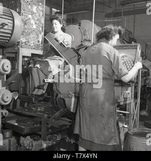 1950, historische, lady Arbeiter mit Maschinen am stets bereit, Batterie Werk in Forest Road, Walthamstow, London, England, UK. Frau eingetragen Beschäftigung in der Industrie in großen Zahlen, die während des Zweiten Weltkriegs und viele hatten nach dem Ende des Krieges. Die Foret Straße Fabrik für die Herstellung von trockenen Batterien für tragbare Radios spezialisiert. Von 1963 überhaupt bereit waren 28 Fabriken in Großbritannien beschäftigt über 12.000 Mitarbeiter. Stockfoto