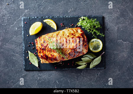 Gebackenes Huhn Hackbraten Terrine auf einem Schiefer ebenen Platte mit Zitronenscheiben und frischem Thymian auf einer konkreten Tabelle, vertikale Ansicht von oben, flach, Eng Stockfoto