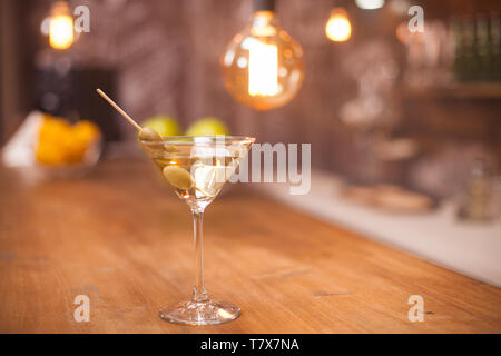 Lecker white Martini mit grünen Oliven auf einen Stock in einem Restaurant, Bar. Feier mit einem guten Martini trinken. Stockfoto