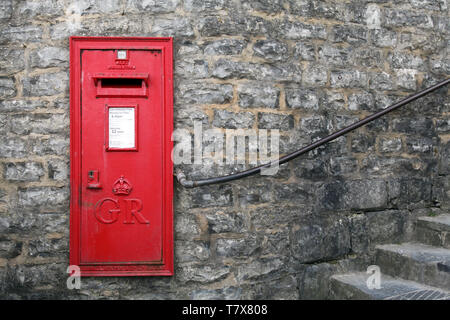 Lyme Regis, Dorset, UK - Classic Red George VI Briefkasten gegen Backsteinwand mit Kopierraum montiert Stockfoto