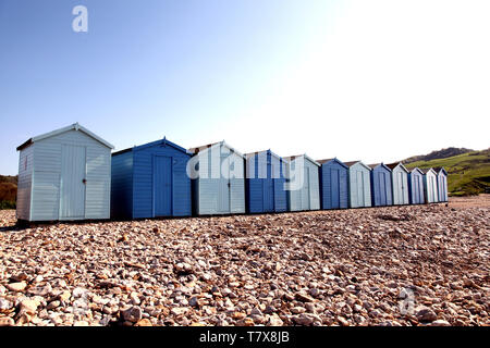 Charmouth Beach, Dorset, UK - Holzstrand Hütten am Kiesstrand in Charmouth mit blauem Himmel im Hintergrund mit Kopierraum Stockfoto