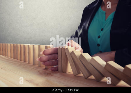 Geschäftsfrau hält eine Kette fallen wie Domino Spiel. Konzept zur Vermeidung der Krise und Ausfall im Geschäft. Stockfoto