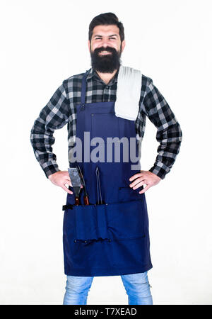 Grill im Freien. Kochen Grill. Hipster in Schürze mit Metallgegenstände, Grill. Bärtiger Mann mit Grill Greifer Werkzeuge in den Taschen. Grill kochen. Die Zubereitung von Speisen am Grill mit einem Grill. Stockfoto