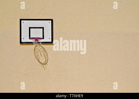 Basketballkorb mit einem Schatten des Net auf eine gelbe Wand Stockfoto
