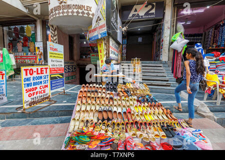 Straßenszene in Mahipalpur Bezirk, einem Vorort in der Nähe von Delhi Flughafen in New Delhi, die Hauptstadt Indiens: lokale Mann bei der Arbeit mit einem manuellen Nähmaschine Stockfoto