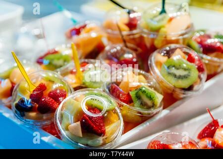 Plastikbecher mit köstlichen Früchte zu verkaufen. Kiwi, Ananas und andere saftige Früchte in Plastikbecher. Takeaway Früchte Stockfoto