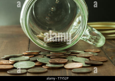 Geld im Glas auf Holztisch Stockfoto