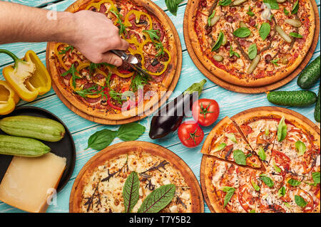 Italienische Pizza am blauen Holz- Hintergrund. Koch schneidet Pizza. italienische Küche. gourmet Pizza Sammlung flach Stockfoto