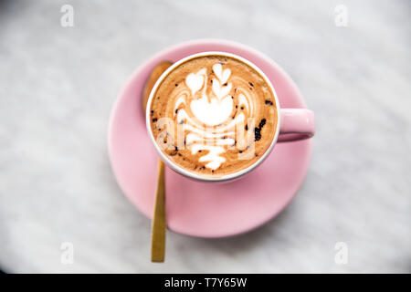 Rosa Tasse Cappuccino mit Swan latte Art auf Marmor tisch Hintergrund. Morgen Konzept. Stockfoto