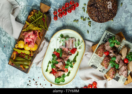 Sie stehen auf einem hellgrauen Hintergrund: ein Board mit eingelegtem Gemüse, eine Platte von caspacho und eine Tafel mit Aufschnitt. Schöne Servieren von Speisen. Restaurant Menü Stockfoto
